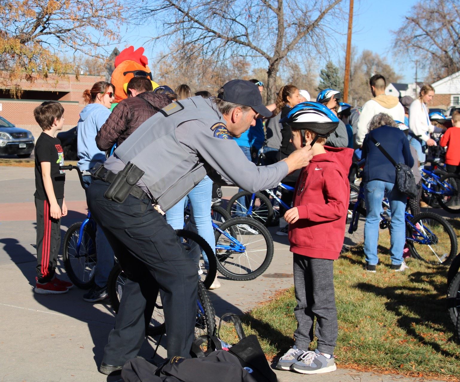 Community Service Officer helping child with putting on a helmet